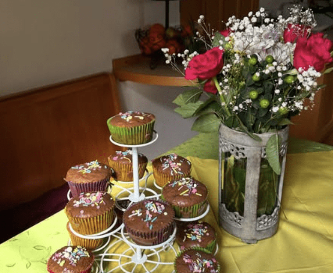 Cupcakes und Blumenarrangement auf Tisch