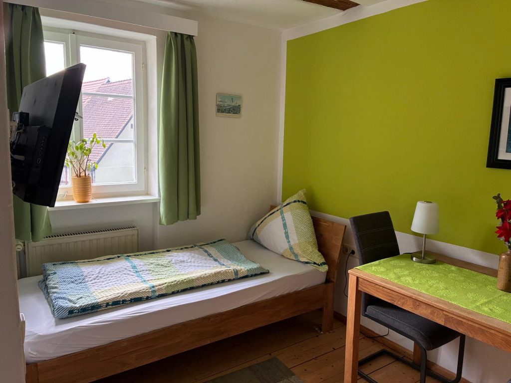 Kleines Zimmer mit Bett und Tisch